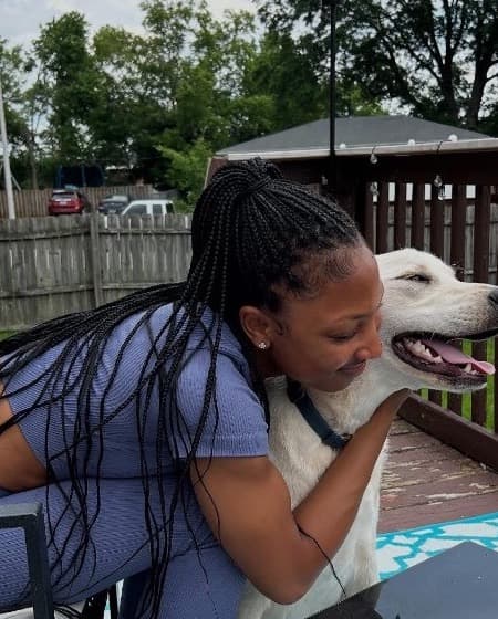 Shai Walker hugging a happy white dog